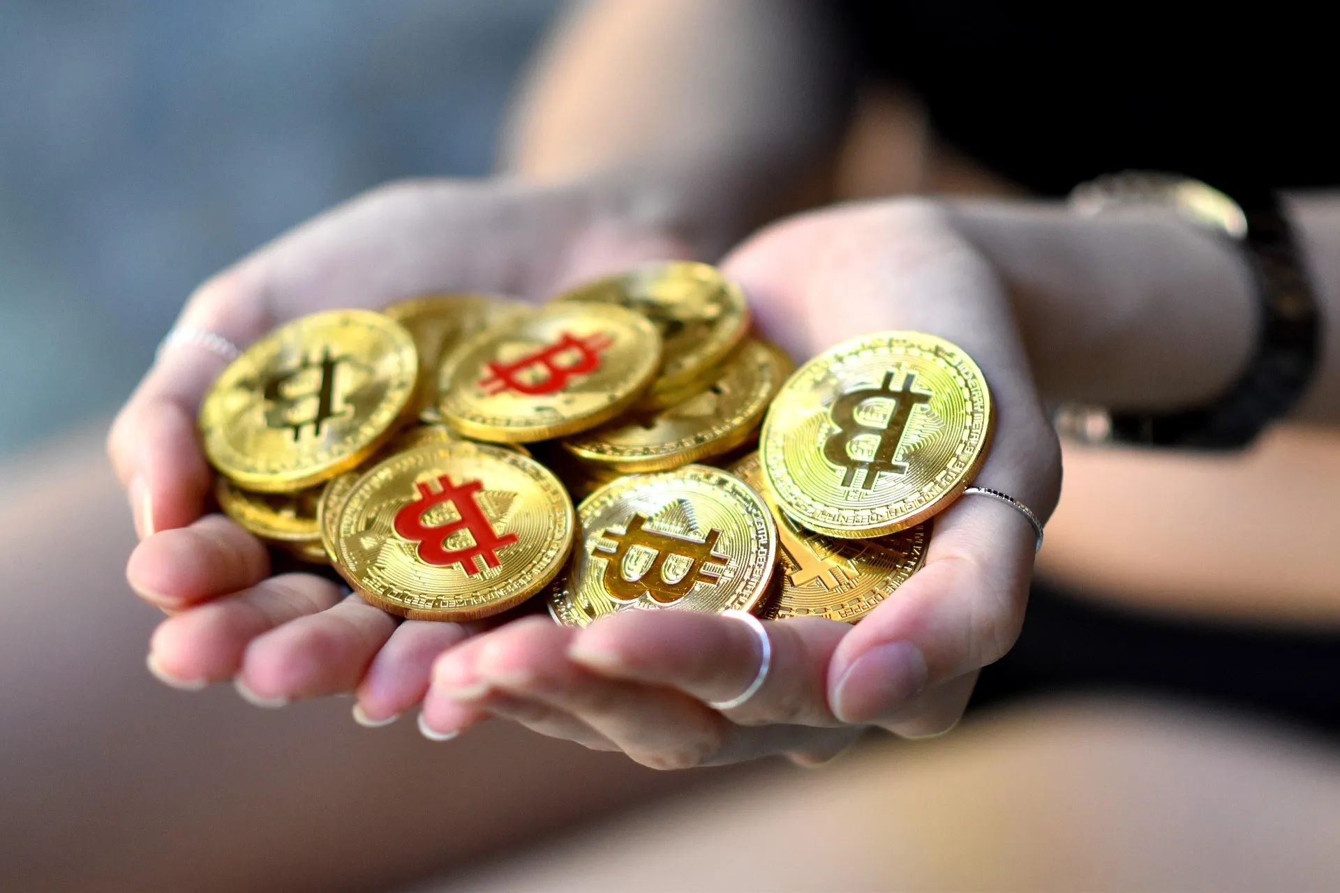A pair of hands holding a pile of physical Bitcoin coins