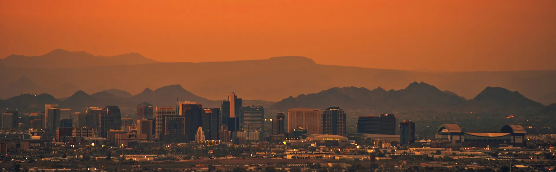 Downtown Phoenix skyline at sunset with the Sonoran mountain ranges behind it
